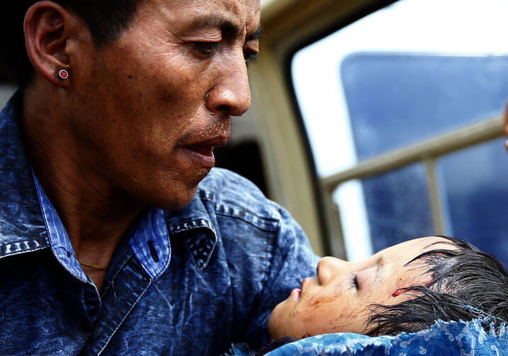 A father holds his injured son after being brought to a hospital April 29 near Kathmandu, Nepal. (CNS photo/Narendra Shrestha, EPA)