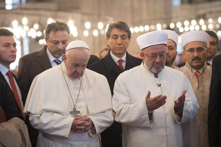 Pope Francis prays with Istanbul's grand mufti Rahmi Yaran during a visit to the Sultan Ahmed Mosque, also known as the Blue Mosque, in Istanbul Nov. 29. (CNS photo/L'Osservatore Romano via Reuters)