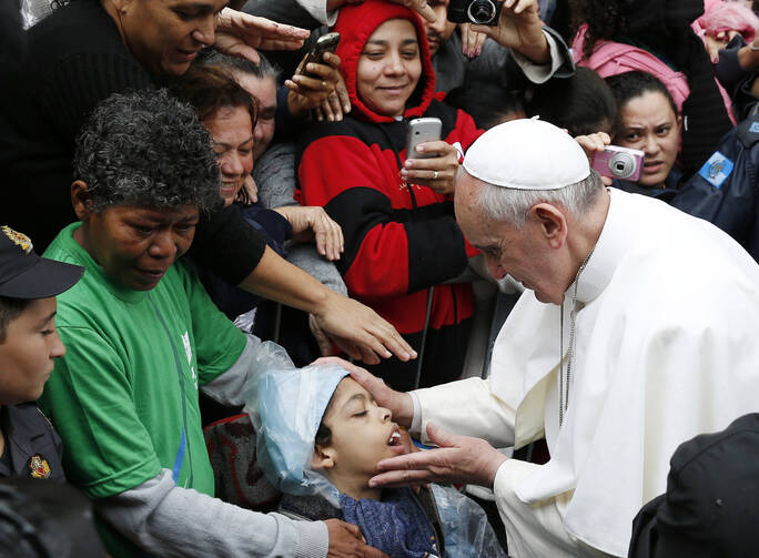 Pope Francis blesses boy during visit to slum complex in Brazil, July 25 (CNS Photo / Paul Haring)