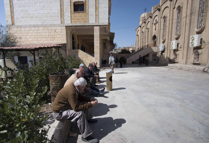 Displaced Assyrians, who fled from the villages around Tel Tamr, Syria, gather in March outside the Assyrian Church in Hassakeh as they wait for news about abductees remaining in Islamic State hands. (CNS photo/Rodi Said, Reuters)