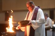 Father Thomas Kommers of St. Joseph Church in Red Wing, Minn., puts palms in a bowl and burns them during an Ash Wednesday prayer service Feb. 10. (CNS photo/Dave Hrbacek, The Catholic Spirit)