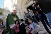 Cardinal Vincent Nichols of Westminster, England, greets children after celebrating Mass. (CNS photo/Mohammed Saber, EPA)