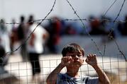 A displaced child from the Moria refugee camp looks over a fence inside a new temporary camp on the Greek island of Lesbos Sept. 23, 2020. (CNS photo/Yara Nardi, Reuters)