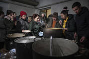 People line up to receive hot food in an improvised bomb shelter in Mariupol, Ukraine, on March 7, 2022. (AP Photo/Evgeniy Maloletka)