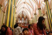 worshippers attend a mass at a cathedral in china, most of the ceiling is seen in the image along with people