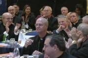 Catholic priests sit at tables for meeting