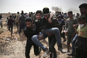 Palestinian protesters evacuate a wounded youth who was shot by Israeli troops during a protest at the Gaza Strip's border with Israel on April 13. Palestinians streamed to tent camps on Gaza's border with Israel for a third mass protest. (AP Photo/ Khalil Hamra)