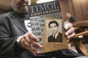 Imtiaz Cajee, nephew of Ahmed Timol, poses with his book about the activist on Aug. 24 in the North Gauteng High Court in Pretoria, South Africa. (AP Photo, File)