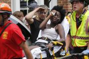 Rescue personnel help an injured woman after a car ran into a large group of protesters after an white nationalist rally in Charlottesville, Va., on Aug. 12. (AP Photo/Steve Helber)