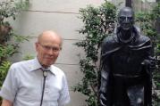 Bob Deiters, S.J. standing next to a statue of St. Ignatius in the courtyard of the Jesuit residence at Sophia University in Tokyo.