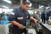 A metalworking student uses a lathe at a Fe y Alegria training center in San Salvador. The Jesuit educational organization uses training to improve the lives of young men and that might otherwise emigrate.