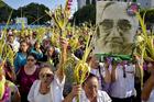 Worshippers wave palm fronds near an image of Blessed Oscar Romero during a Palm Sunday procession March 25 in San Salvador, El Salvador. Catholic officials in El Salvador were shaken and expressed outrage and sadness after the assassination of a 36-year-old priest during Holy Week, in what some suspect may be a gang killing. (CNS photo/Armando Escobar, EPA)