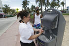 Maria Gomez, foreground, washes her hands at a public sink in Miami Beach, Fla., on June 22. (AP Photo/Wilfredo Lee)