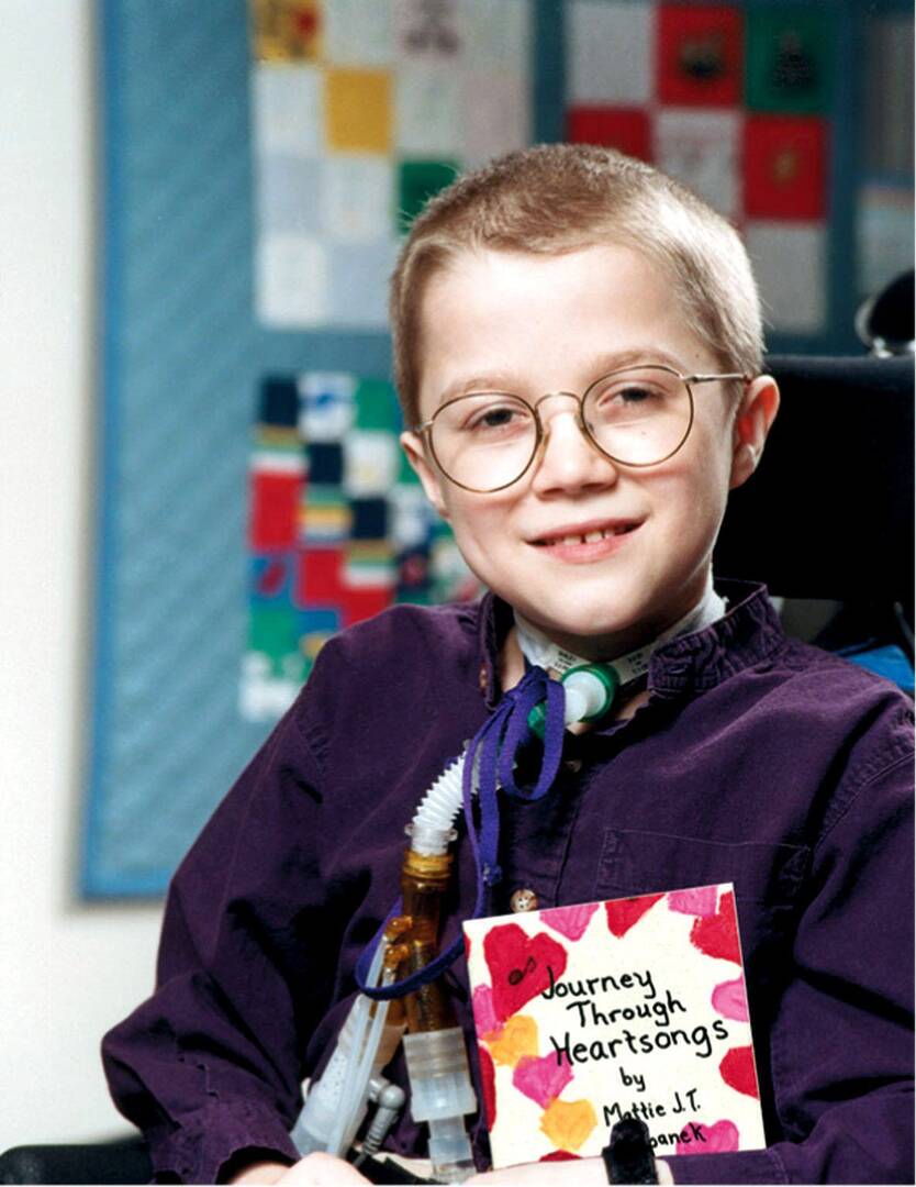 mattie stepanek, a young boy in glasses, smiles while holding a book he wrote