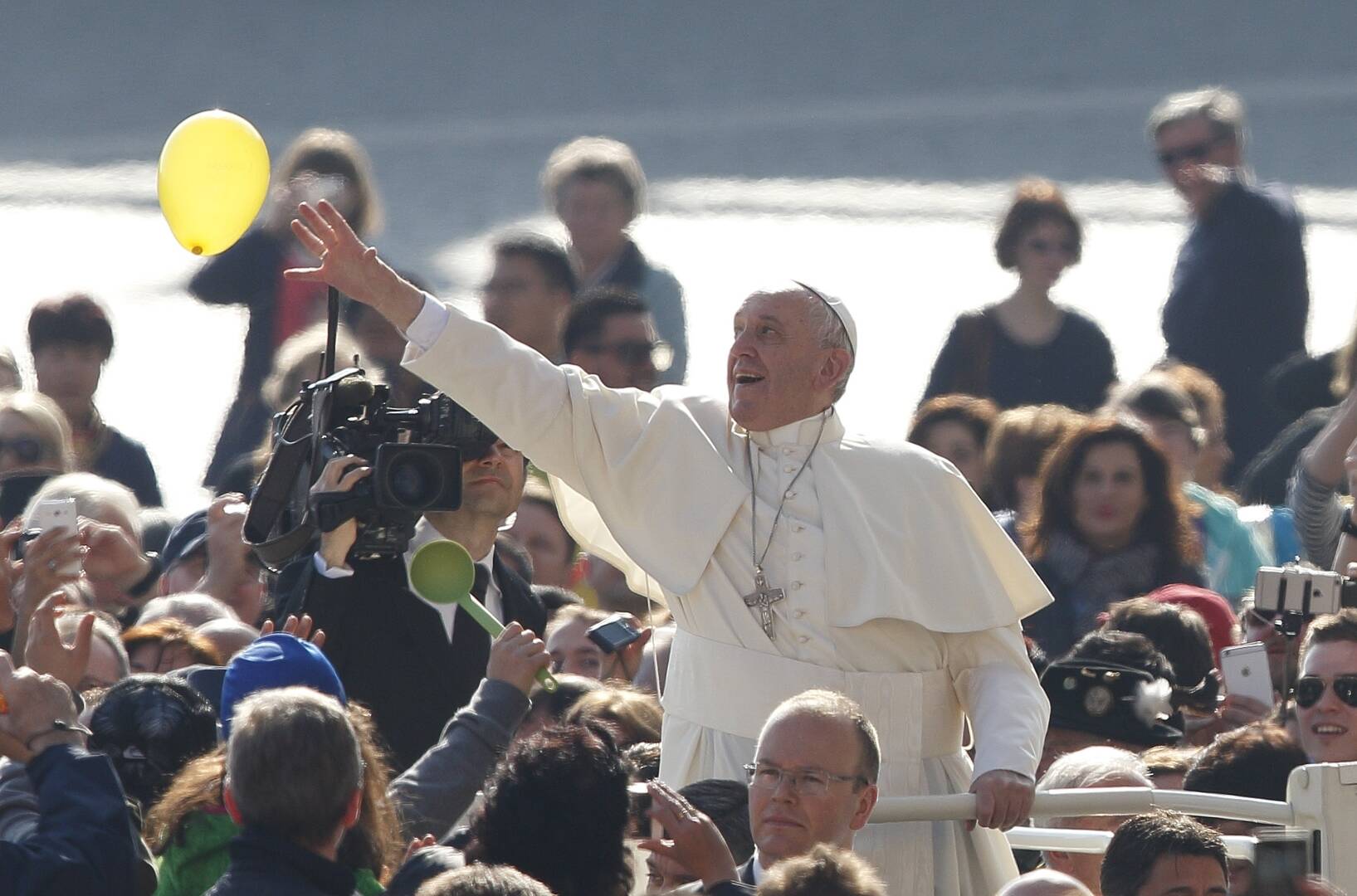 Pope Francis reaches out to touch a yellow balloon while smiling (Credit: Paul Haring)