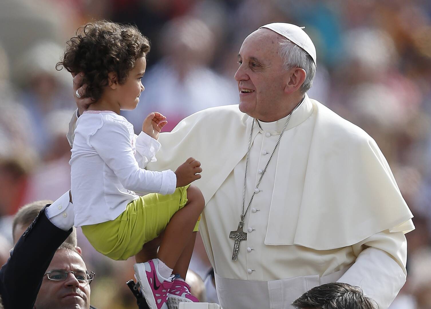 pope francis greets a toddler at a general audience in 2013, the child is wearing a long sleeve shirt and has curly hair