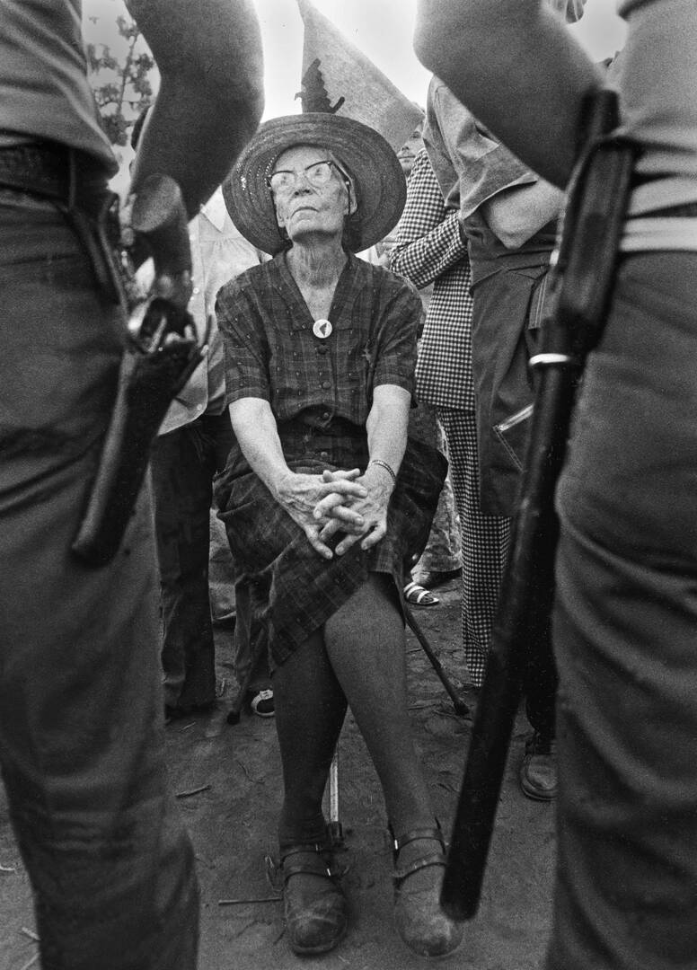 dorothy day sits in an iconic photo surrounded by police who are arresting her as she is elderly