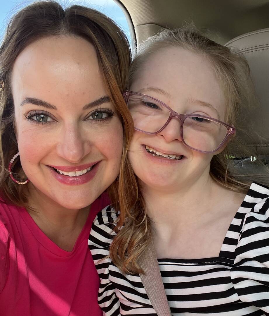 the author smiles with her daughter who wears pink glasses and has down syndrome