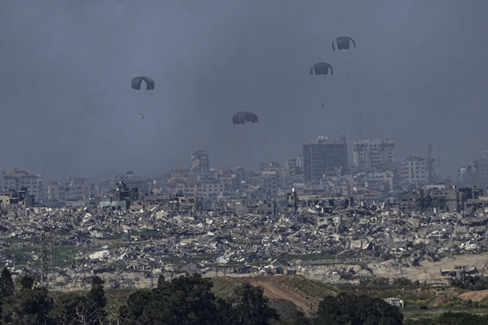 Parachutes drop supplies into the northern Gaza Strip, as seen from southern Israel on March 13. (AP Photo/Tsafrir Abayov)