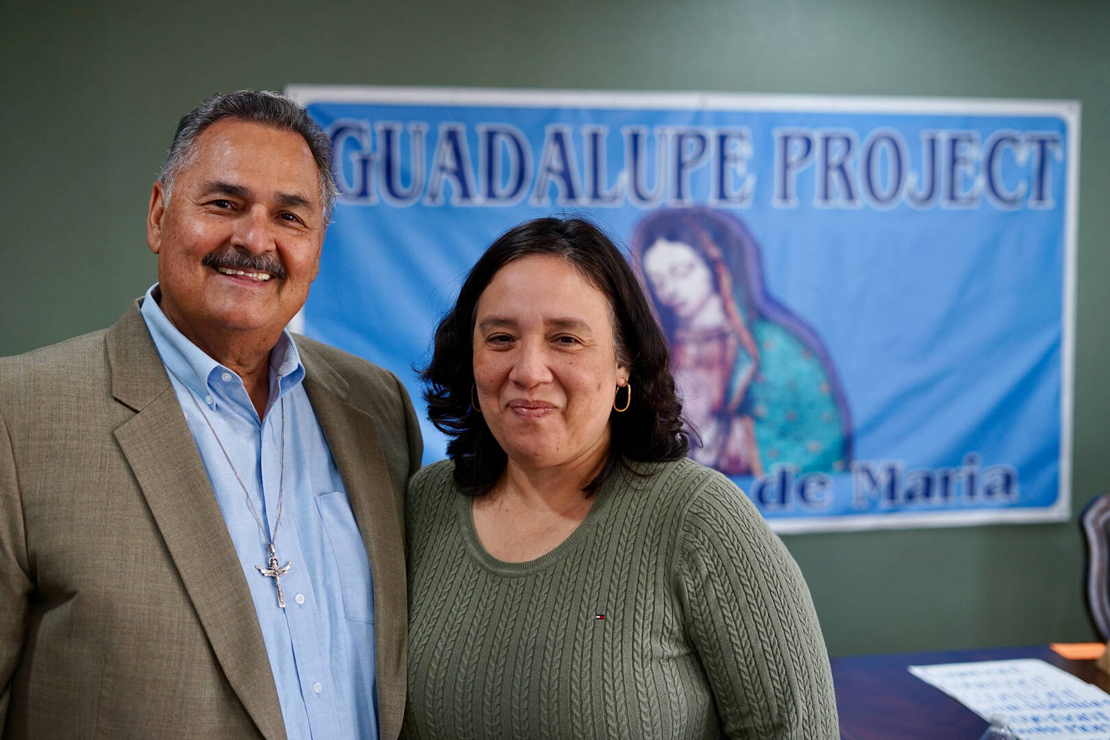 a hispanic couple armando and monica ruiz stands in front of an our lady of guadalupe sign