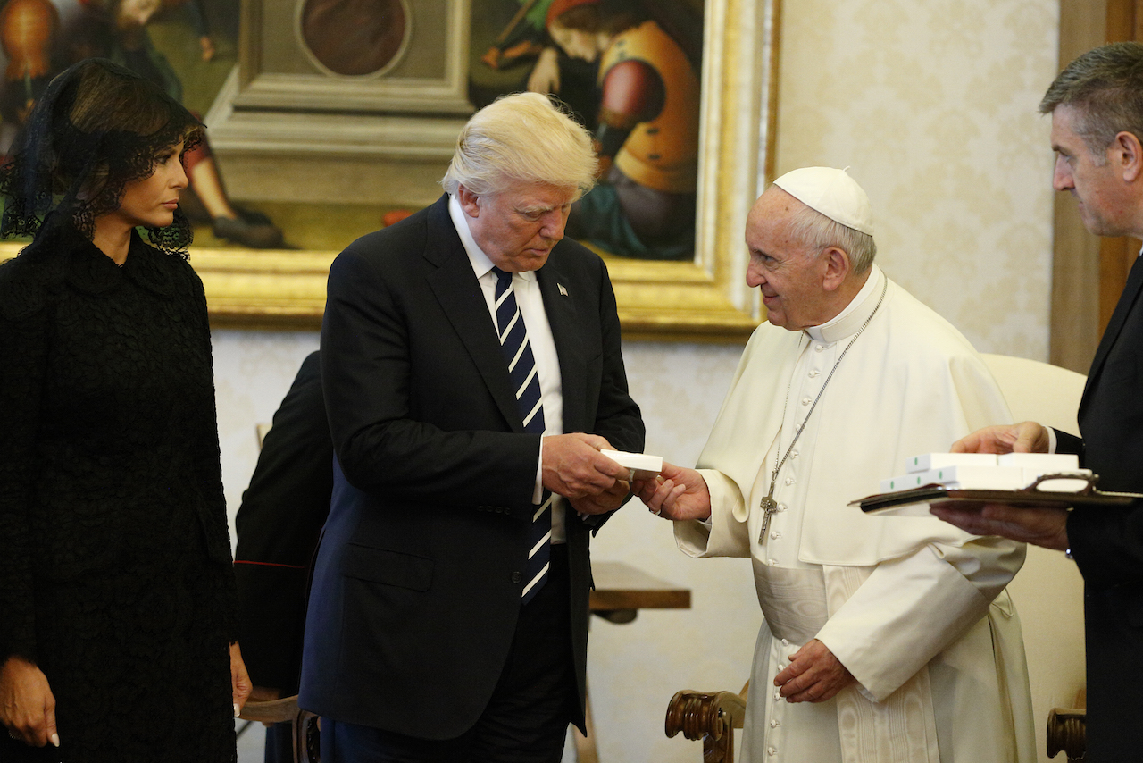 Pope Francis presents a gift to U.S. President Donald Trump, accompanied by his wife, Melania, during a private audience at the Vatican May 24. (CNS photo/Paul Haring)