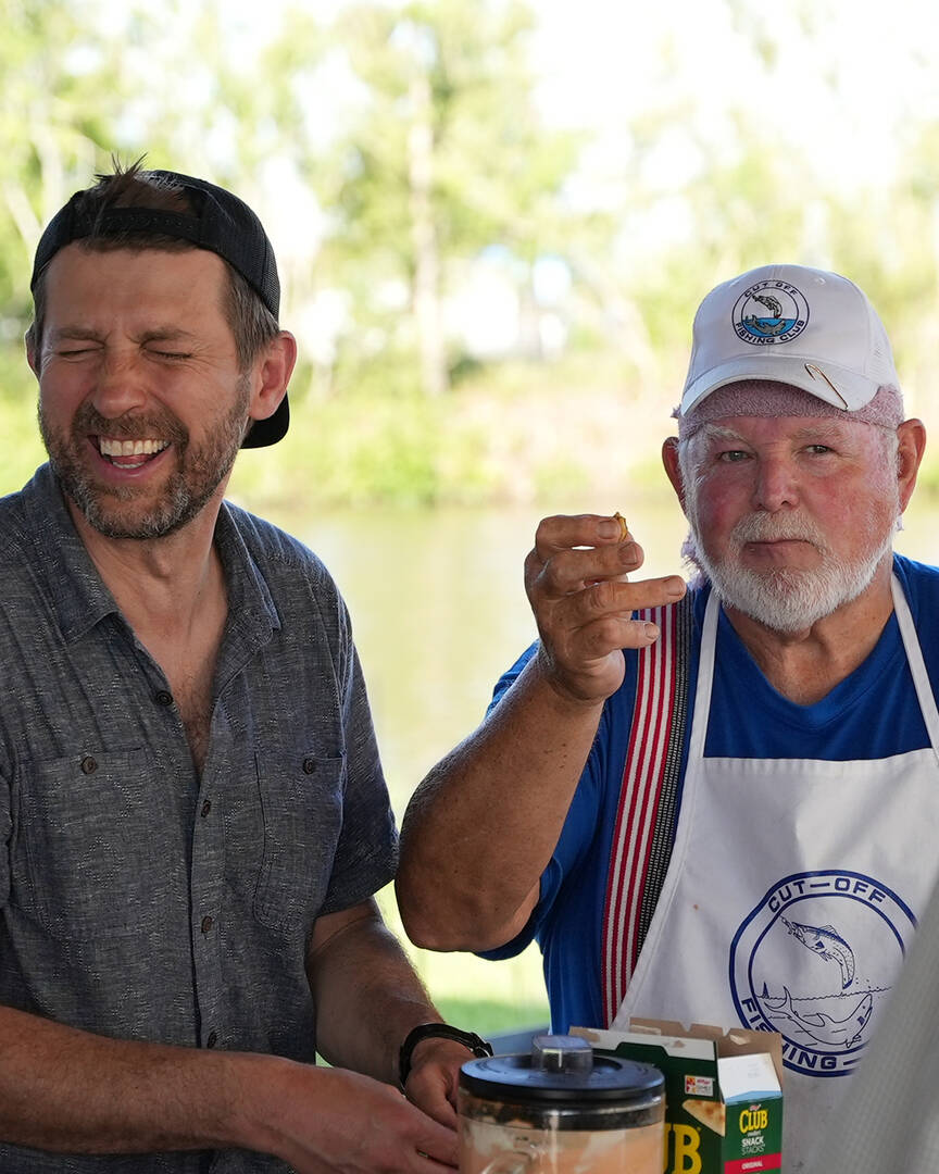 Deniz Demirer (left), director of photography for America Media, tries a mysterious new food at the Cut Off Fishing Club “Tin Shed” in Cut Off, La.