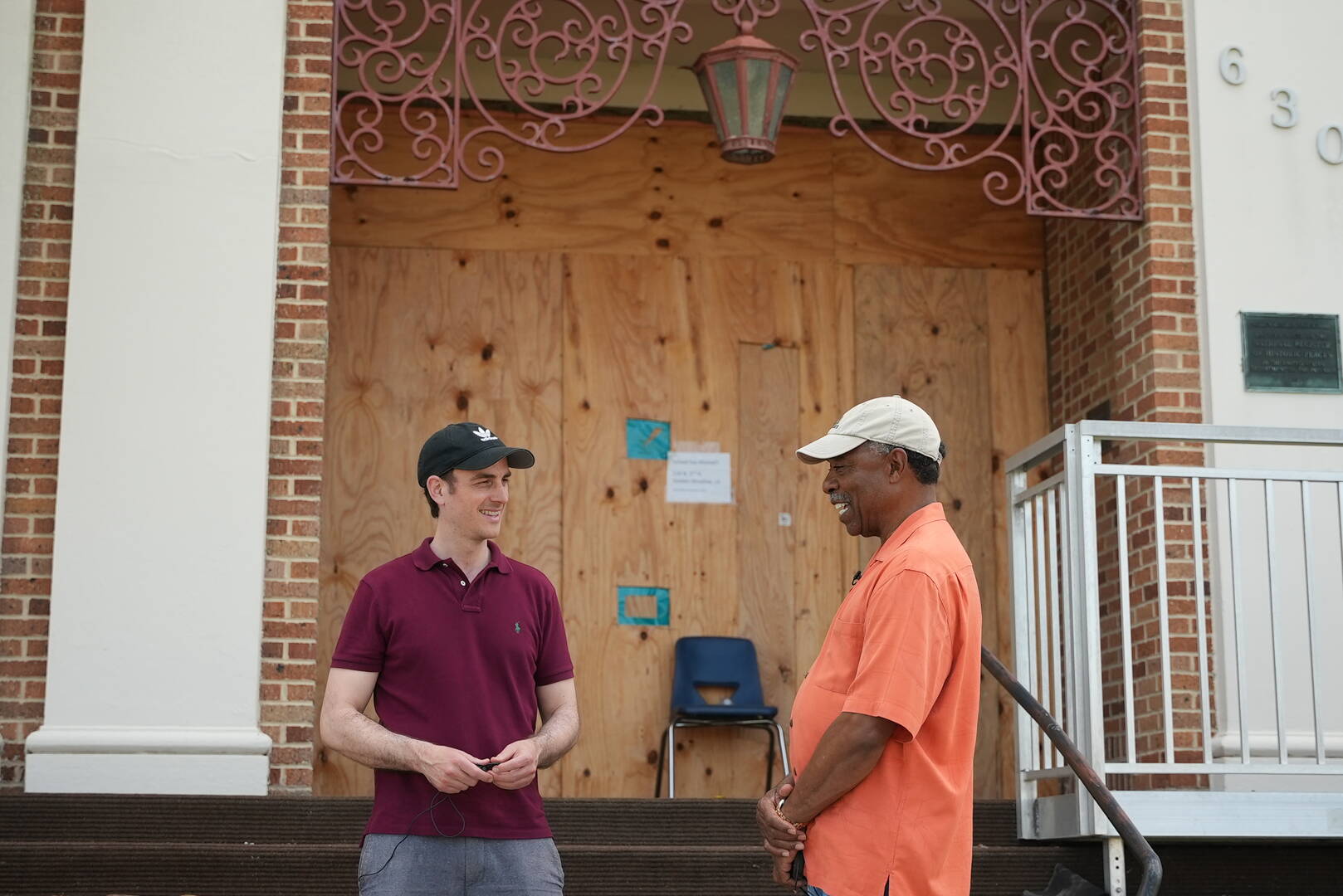 Al Archer (right), parishioner at Sacred Heart Catholic Church, talks with Sebastian Gomes of America Media outside a hurricane-damaged middle school in Golden Meadow, La.