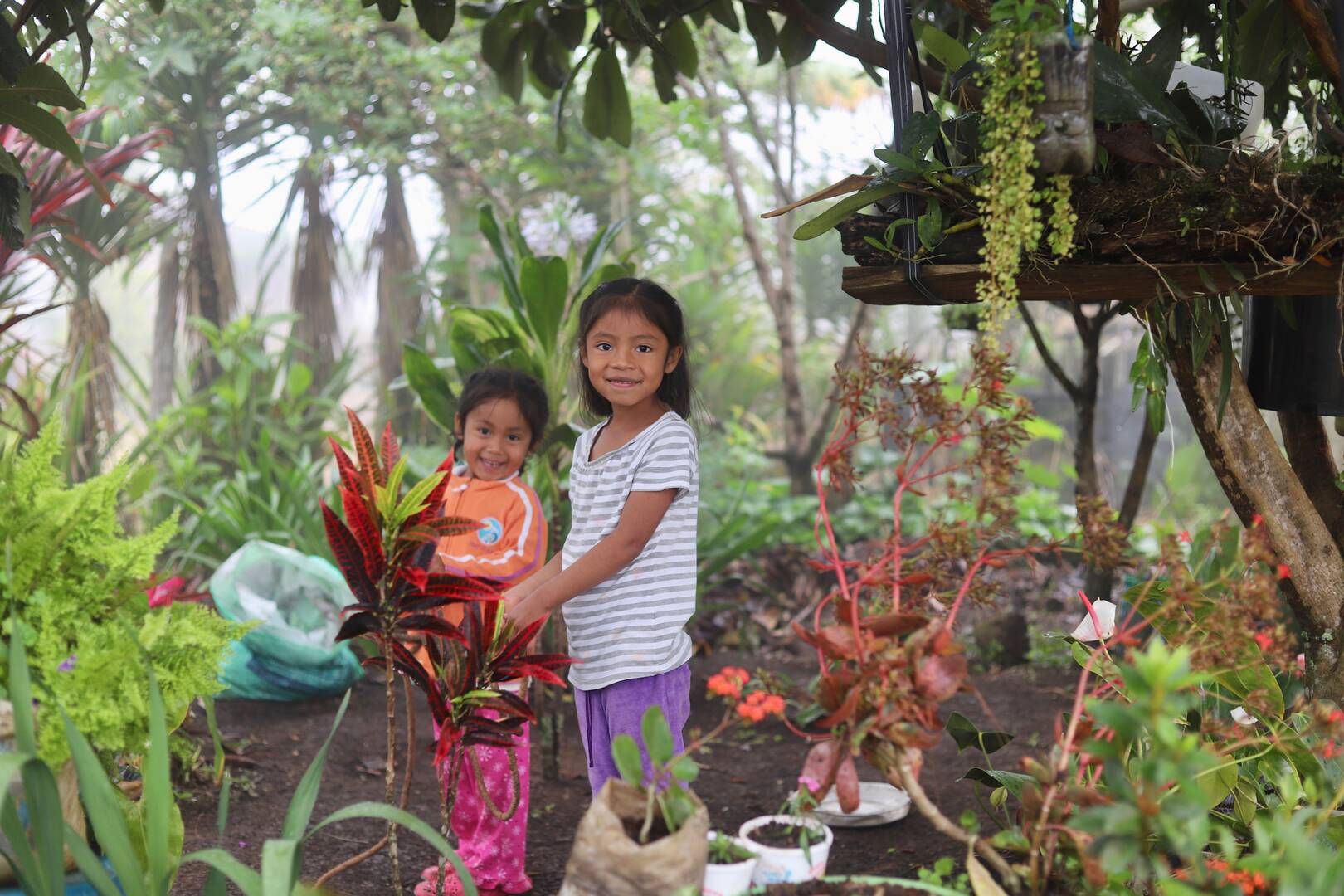 Two Honduran children play in a family garden