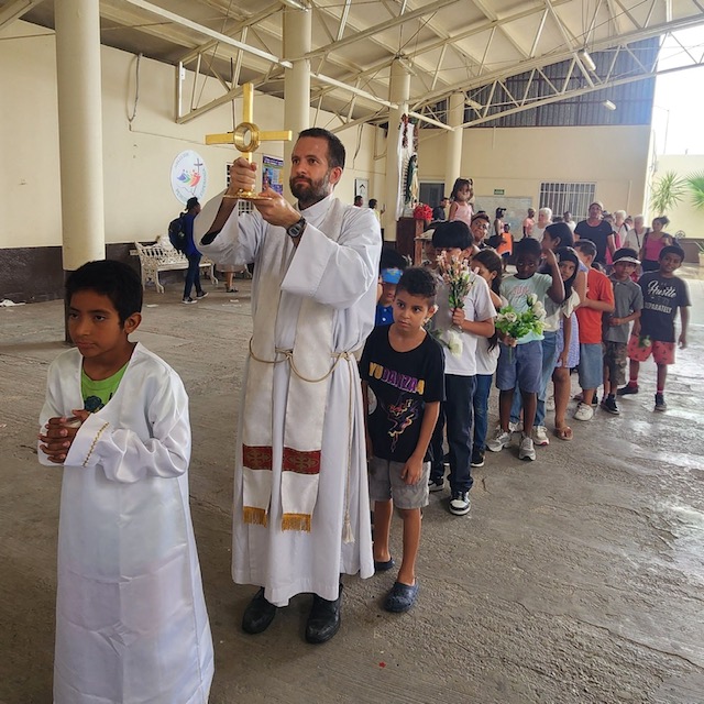  Brian Strassburger, S.J., leads a Corpus Christi procession at Casa del Migrante in Reynosa, Mexico. (Photo provided by authors) 