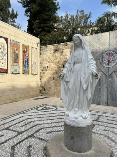 Statue of Mary in Jerusalem. As the author describes, the paint on her hands has been chipped away by the touch of many visitors.
