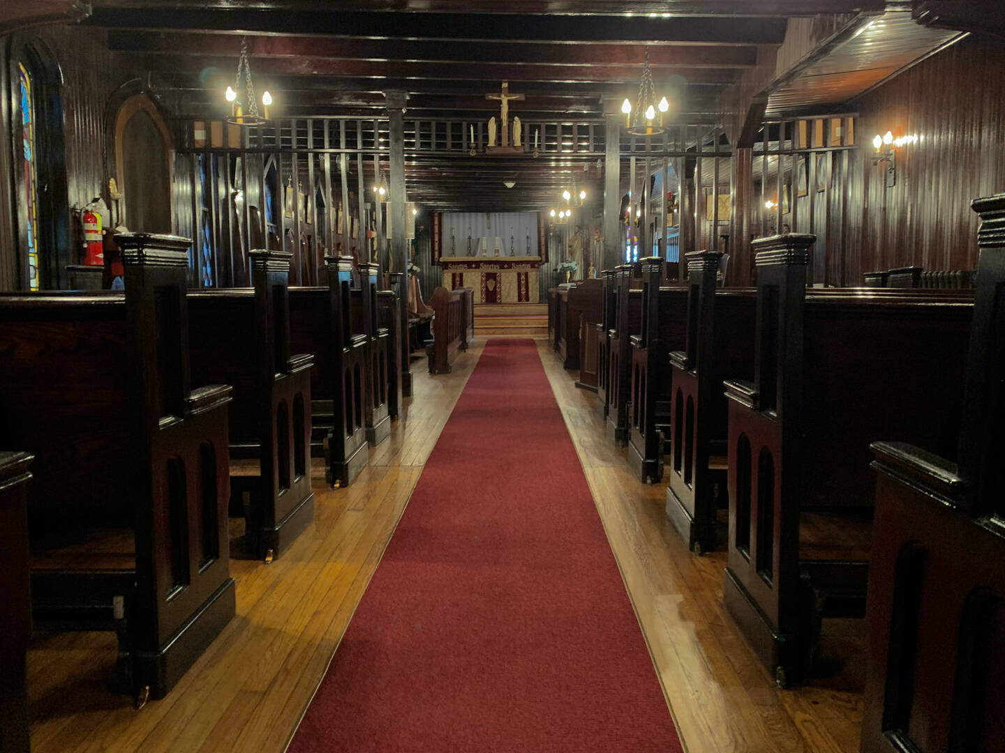 Our Lady of the Angels Chapel, with dark wooden pews and a red carpet leading to the altar