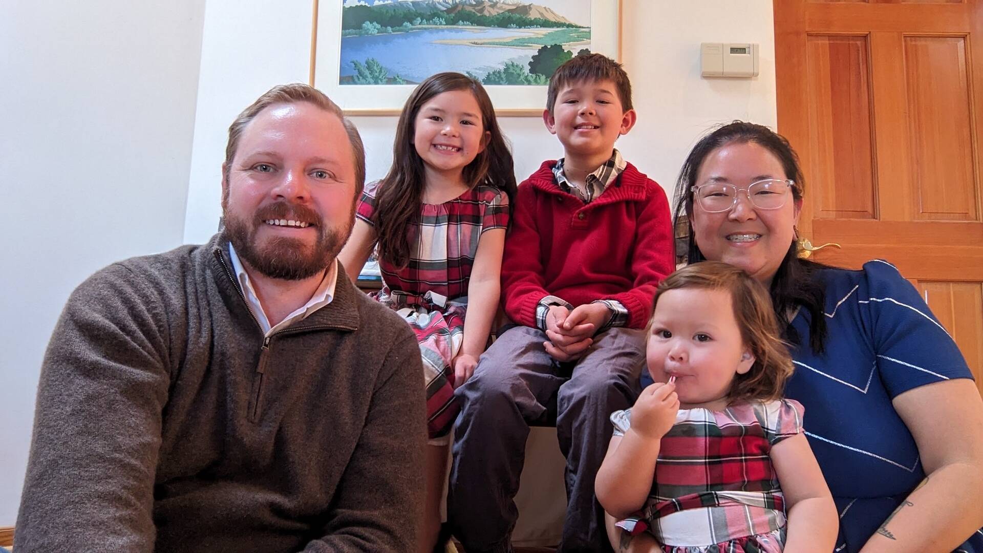 the frese family poses for a photo, the father has red hair, the mother is of asian descent and their three young kids have brown hair