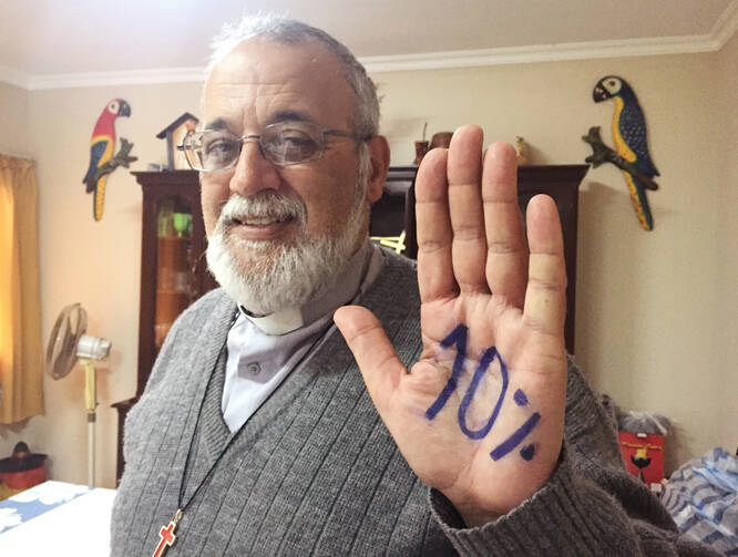 Camillian Father Mateo Bautista Garcia shows his hand with "10%" written on it. The priest wants Bolivia's government to spend 10 percent of its budget on health care. (CNS photo/David Agren)