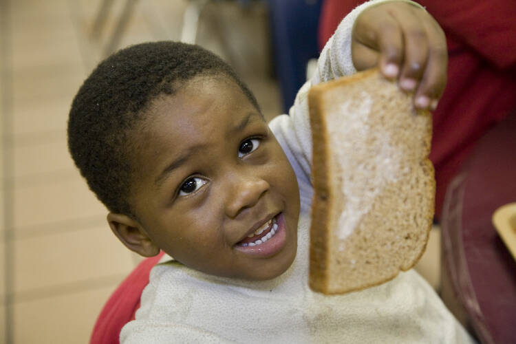 Three-year-old Matthew Malone shows off part of his lunch at the Capuchin Soup Kitchen in Detroit Nov. 13. (CNS photo/Jim West)