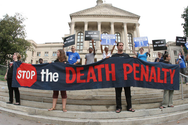 People hold a banner and signs on the steps of the Georgia Capitol in Atlanta during a vigil for death-row inmate Troy Davis before his Sept. 21 execution. (CNS photo/Michael Alexander, Georgia Bulletin)