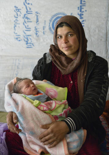 Photo: Raghad Al-Hussein, a 30-year-old Syrian refugee, holds her newborn child inside their makeshift shelter in the village of Jeb Jennine, in Lebanon on Nov. 22. CNS Photo: Paul Jeffrey.)