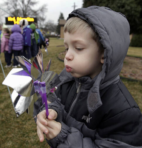 Pre-K student Patrick Meade plays with a pinwheel April 9 as students of St. Thecla School in Chicago mark National Child Abuse Prevention Month.