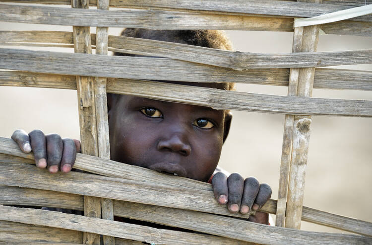 Boy displaced by conflict peers through fence in contested Sudanese border region. (CNS photo/Paul Jeffrey)