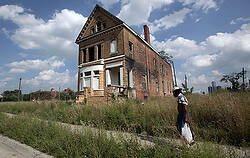 Man walks past a vacant home in Detroit neighborhood (CNS photo)