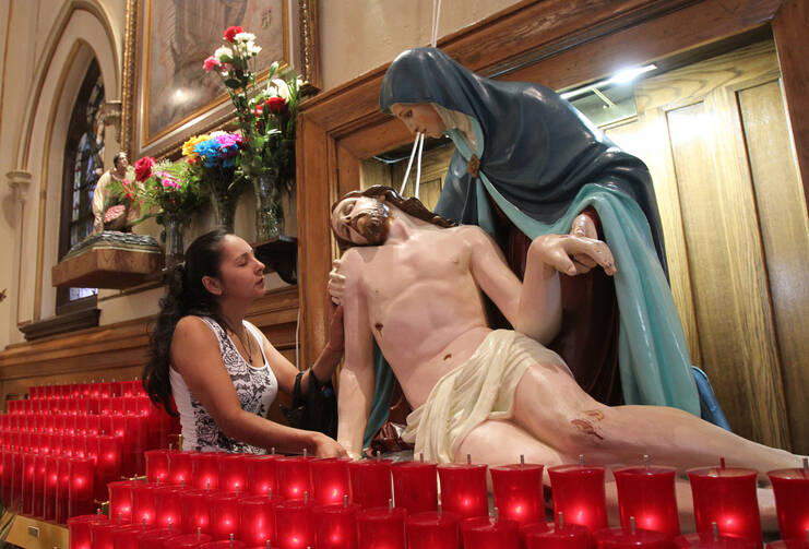 A woman touches a statue of Jesus and Mary as she prays at Our Lady of Sorrows Church in the Corona neighborhood of the New York borough of Queens. (CNS photo/ Gregory A. Shemitz)