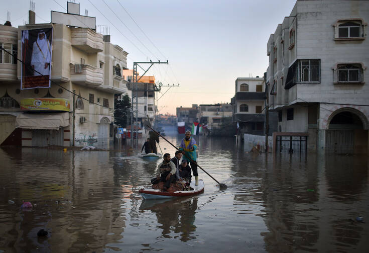 Palestinian civil defense volunteers paddle boat to evacuate people after flooding in Gaza Strip. (CNS photo/Mohammed Salem, Reuters) 