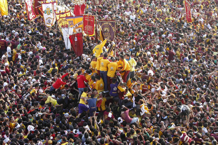 Pilgrims climb to touch statue of Black Nazarene during procession in Manila. (CNS photo/Romeo Ranoco, Reuters)