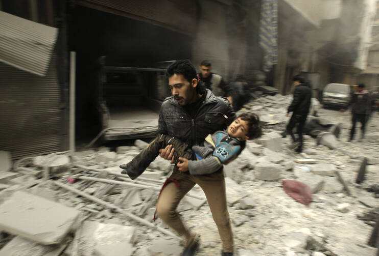 A man runs while carrying a child who survived what activists say was an airstrike by forces loyal to Syrian President Bashar Assad in Aleppo Jan. 21. (CNS photo/Ammar Abdullah, Reuters)