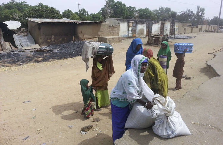 Woman with children pack what is left of their belongings following attack in Nigeria. (CNS photo/Reuters) 