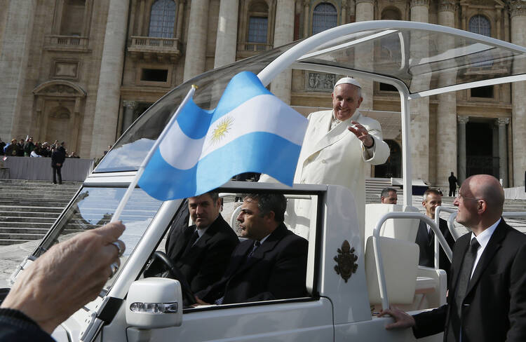 Pilgrim waves Argentina's flag as Pope Francis leaves general audience in St. Peter's Square at Vatican. (CNS photo/Paul Haring)