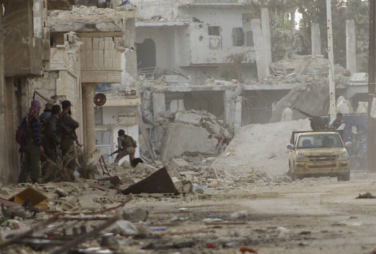 Free Syrian Army fighter runs amid destroyed buildings during clashes with forces loyal to Syria's President Bashar Assad in the town of Morek on March 11. (CNS photo/Rasem Ghareeb, Reuters)