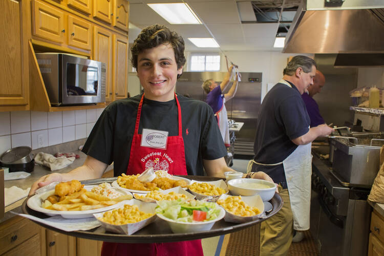 Young volunteer displays food prepared for dinners at a Friday evening fish fry in a Detroit parish. (CNS photo/Jim West)