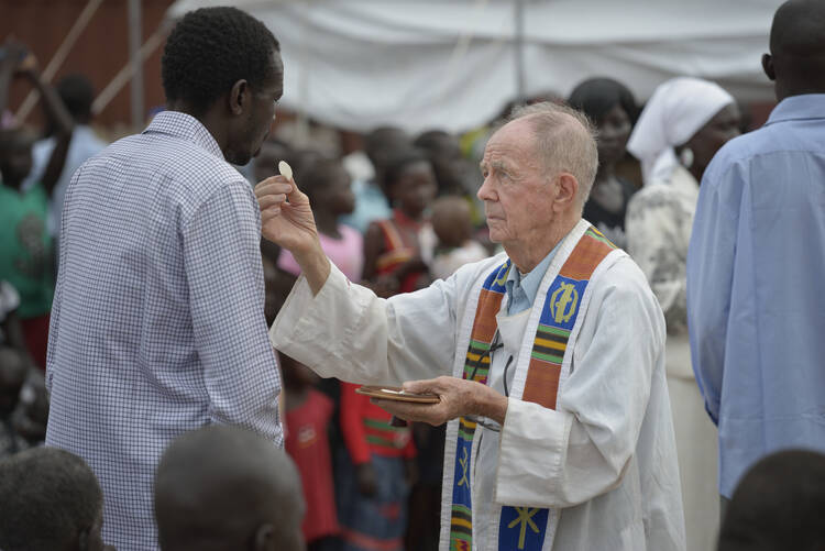 Jesuit Father Michael Schultheis distributes Communion during Mass held in a camp for internally displaced families inside a U.N. base in Juba, South Sudan. (CNS photo/Paul Jeffrey)