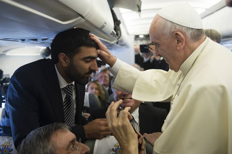 Pope Francis blesses journalist aboard papal flight en route to Amman. (CNS photo/L'Osservatore Romano via Reuters) 