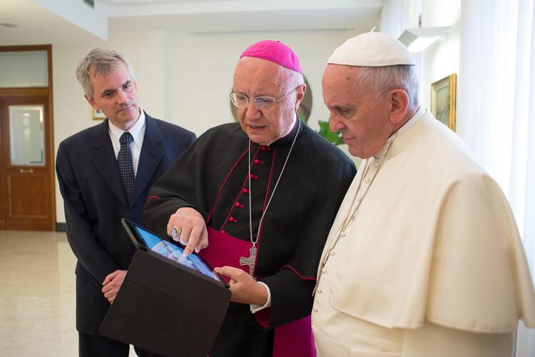 Archbishop Claudio Celli, president of the Pontifical Council for Social Communications, center, shows Pope Francis news on a tablet during a meeting at the Vatican July 7. (CNS photo/L'Osservatore Romano via Reuters) 